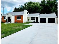 Charming ranch home with white and wood siding, a two-car garage, and a landscaped lawn at 210 W Illiana St, Orlando, FL 32806