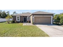 House exterior featuring a two-car garage and well-maintained lawn at 7878 Tanbier Dr, Orlando, FL 32818