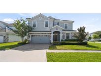 Two-story house with gray siding, stone accents, and a two-car garage at 9098 Hazard St, Davenport, FL 33896
