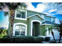 Two-story house with green exterior and palm trees at 2605 Emerald Island Blvd, Kissimmee, FL 34747