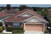 Two-story house with a peach garage door and a nicely landscaped front yard at 662 Rosselli Blvd, Davenport, FL 33896