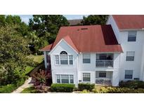 White two-story condo with red roof, balcony, and landscaping at 11574 Westwood Blvd # 1127, Orlando, FL 32821