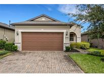 Beige house with brown garage door and brick driveway at 793 Asturias Rd, Davenport, FL 33837