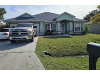 One-story house with light green exterior, landscaping, and driveway at 959 Nancy Ct, Kissimmee, FL 34759