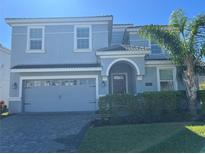 Two-story house with gray siding, a three-car garage, and manicured lawn at 8830 Interlocking Ct, Davenport, FL 33896