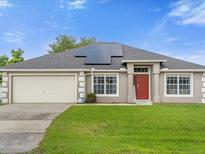 Single-story home with a two-car garage and solar panels at 617 Brockton Dr, Kissimmee, FL 34758