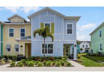 Two-story light blue house with yellow accents, palm tree, and landscaping at 3184 Caribbean Soul Dr, Kissimmee, FL 34747