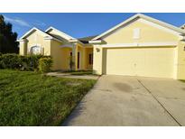 Yellow house with two-car garage and landscaped yard at 2221 The Oaks Blvd, Kissimmee, FL 34746