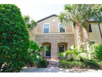Two story townhome with tan siding, double doors, and lush landscaping at 2022 Majorca Dr, Kissimmee, FL 34747