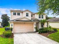 Two-story house with beige exterior, attached garage, and manicured landscaping at 844 Suffolk Pl, Davenport, FL 33896