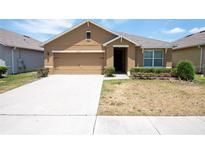 Tan one-story house with two-car garage and landscaping at 1843 Brockridge Rd, Kissimmee, FL 34744