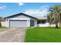 Brick ranch house with a gray garage door and a palm tree in the front yard at 7414 Betty St, Winter Park, FL 32792