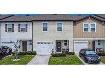 Exterior view of a charming townhome with a two-car garage and well-maintained landscaping at 350 Madison Dr, Davenport, FL 33837