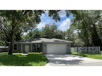 Newly built home with gray exterior, landscaped yard, and a two-car garage at 1730 Old Apopka Rd, Apopka, FL 32703