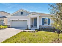 One-story home with gray siding, stone accents, and a two-car garage at 4043 Bannock Ave, Tavares, FL 32778