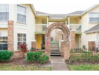 Two-story building with brick arch entryway, lush landscaping, and inviting yellow exterior at 5012 Laguna Bay Cir # 74, Kissimmee, FL 34746