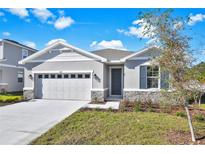 One-story home with gray siding, stone accents, and a two-car garage at 4063 Bannock Ave, Tavares, FL 32778