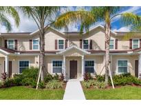 Tan three-story townhome with brown door, walkway, and landscaping at 3227 Cupid Pl, Kissimmee, FL 34747