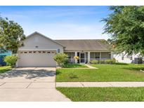 Single-story home with two-car garage and landscaped lawn at 2419 Willow Tree Ln, Kissimmee, FL 34758