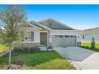 One-story home with stone and siding exterior, two-car garage, and landscaped lawn at 4252 Sawtooth Ct, Tavares, FL 32778