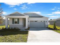 One-story home with gray siding, stone accents, and a two-car garage at 4256 Sawtooth Ct, Tavares, FL 32778