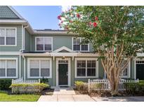 A charming two-story townhome with a green exterior, white picket fence, and landscaping at 2200 San Christabolo Dr # 105, Kissimmee, FL 34741