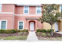 Two-story townhome with peach-colored exterior, walkway, and landscaping at 3006 Red Ginger Rd, Kissimmee, FL 34747