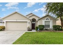 Tan one-story house with a two-car garage and landscaped yard at 170 Thornbury Dr, Kissimmee, FL 34744