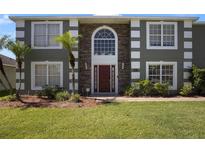 Front exterior of a two-story house with a stone facade, green siding, and a red front door at 5051 Plymouth Turtle Cir, St Cloud, FL 34772