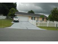 Ranch-style home with a long driveway and white picket fence at 267 Cranbrook Dr, Kissimmee, FL 34758