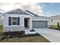 One-story home with gray siding, stone accents, and a two-car garage at 4244 Sawtooth Ct, Tavares, FL 32778