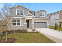 Two-story house with gray siding, stone accents, and a gray garage door at 4255 Sawtooth Ct, Tavares, FL 32778