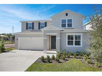 Two-story house with light beige siding, gray shutters, and a two-car garage at 308 Alexandrite St, Deland, FL 32720