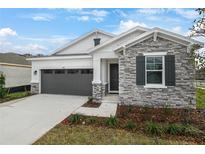 New single-story home with stone and shingle accents, two-car garage, and landscaped front yard at 4056 Bannock Ave, Tavares, FL 32778