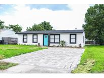 Newly renovated home with a modern exterior, paver driveway, and lush lawn at 1411 Overdale St, Orlando, FL 32825