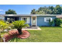 Charming blue house with a well-manicured lawn and mature landscaping at 1206 Osceola Ave, Tavares, FL 32778