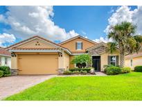 Tan two-story house with a large garage and lush landscaping at 316 Treviso Dr, Poinciana, FL 34759