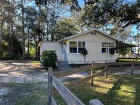 Cute yellow house with a wooden fence and mature trees at 6790 Bass Hwy, St Cloud, FL 34771