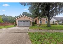 Tan two-car garage home with mature tree in the front yard at 2771 Cedaridge Cir, Clermont, FL 34711