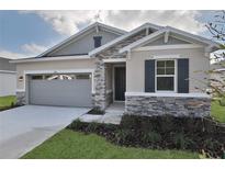 One-story home with gray siding, stone accents, and a two-car garage at 4216 Sawtooth Ct, Tavares, FL 32778
