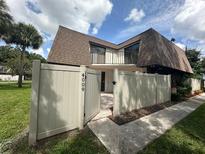 Townhouse with brown roof, gated entrance, and landscaped yard at 4009 Shannon Brown Dr, Orlando, FL 32808