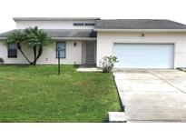 House exterior featuring a one-car garage and palm trees at 348 Jacksonville Ct, Kissimmee, FL 34759