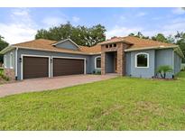 Two-story house with gray siding, brown roof, and two-car garage at 7166 Oak Glen Trl, Harmony, FL 34773