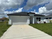 Modern, single story home with a white garage door and driveway at 1204 Vero Beach Way, Poinciana, FL 34759