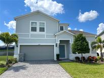 Two-story house with gray siding, gray garage door, and landscaping at 2290 Lelani Cir, Davenport, FL 33897