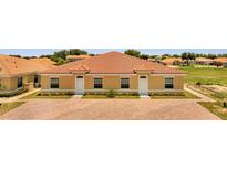 Exterior view of a light-yellow, three-unit building with a red tile roof and brick driveway at 1808 Coriander Dr, Kissimmee, FL 34759