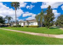 Single-story home with a red door, lush lawn, and palm trees at 2918 Sunset Retreat Ct, Kissimmee, FL 34747