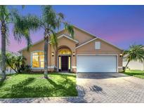 Tan two-story house with a dark brown door and lush landscaping at 621 Knightsbridge Cir, Davenport, FL 33896