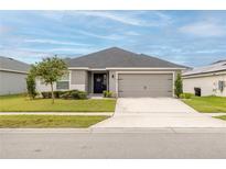 One-story home with gray siding, gray garage door, and landscaping at 872 Sydney St, Davenport, FL 33837