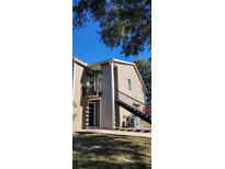 Tan colored siding condo building with a black metal staircase and balcony at 4768 Walden Cir # 327, Orlando, FL 32811